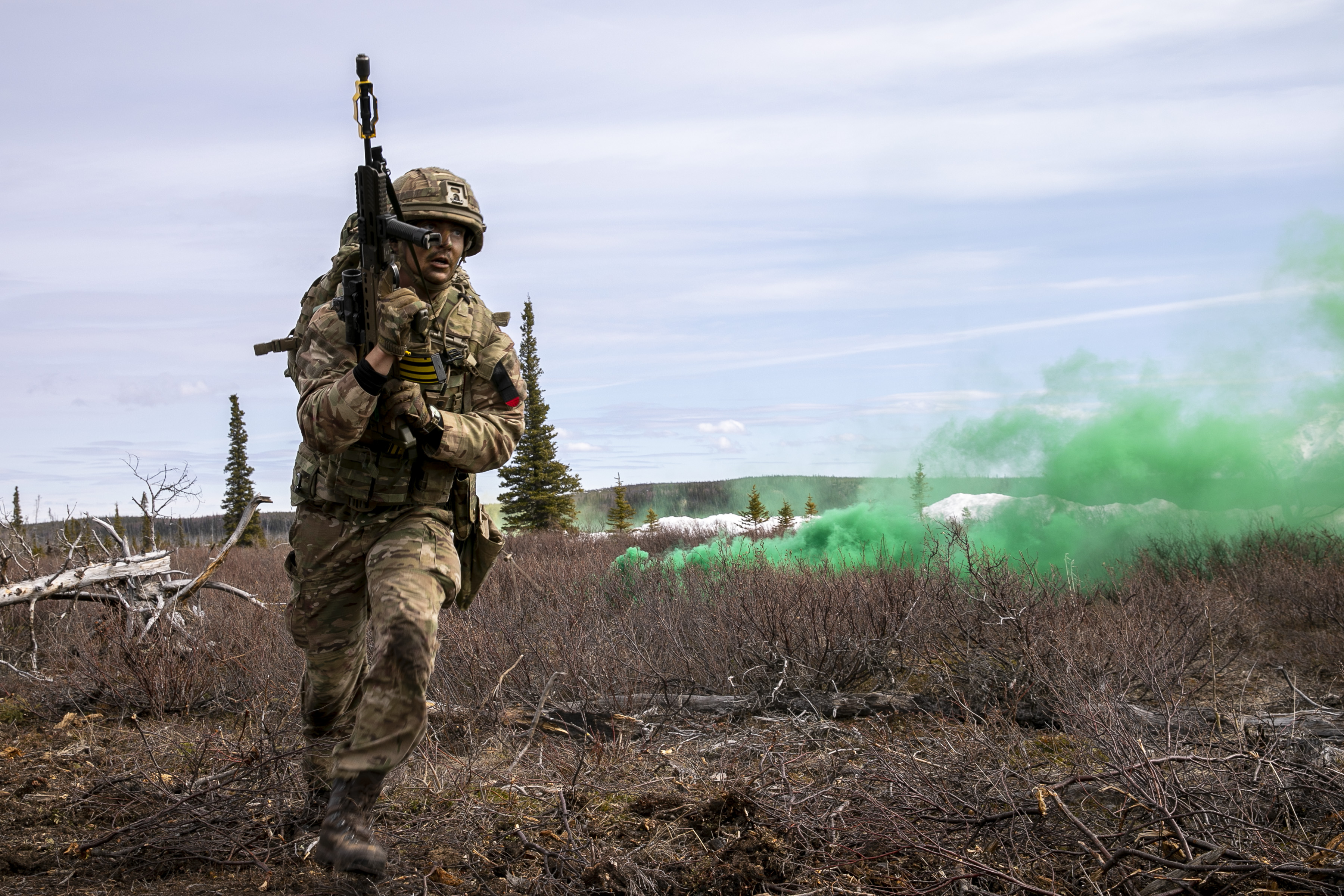 RAF Regiment with rifle runs away from green flare.